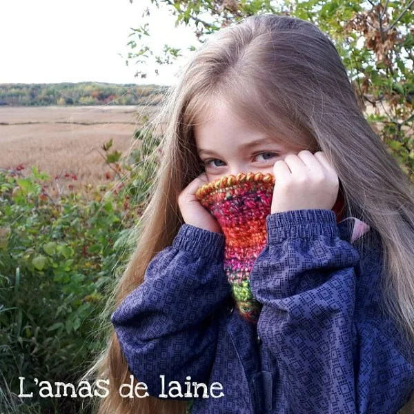 A girl in the countryside with a brightly coloured crochet cowl.