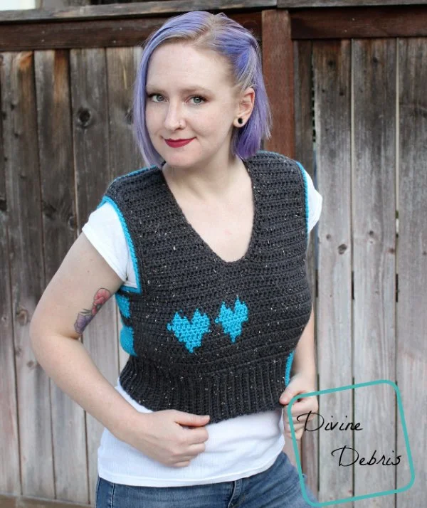 A woman with a fitted, cropped crochet sweater vest with love heart motifs.