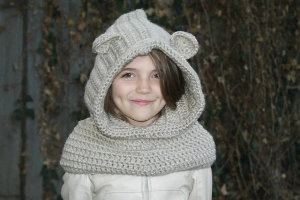 A girl wearing a hooded crochet bear cowl.