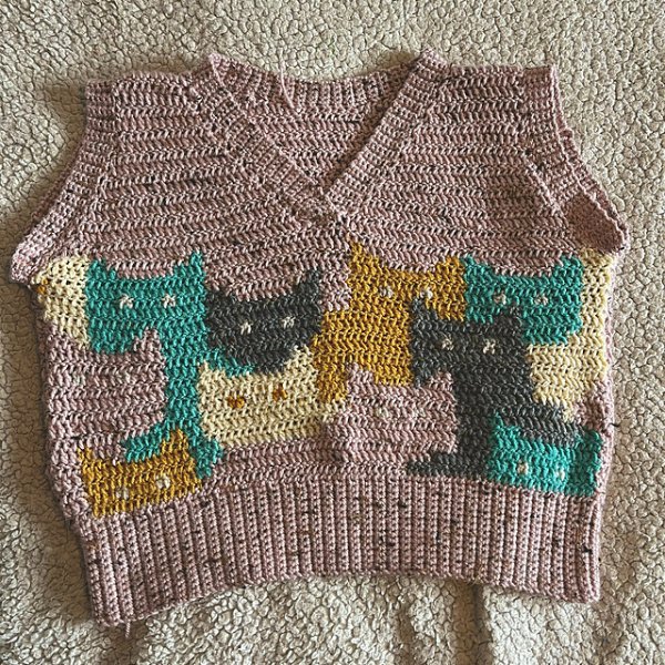 A crochet sweater vest with featuring colourwork cats.