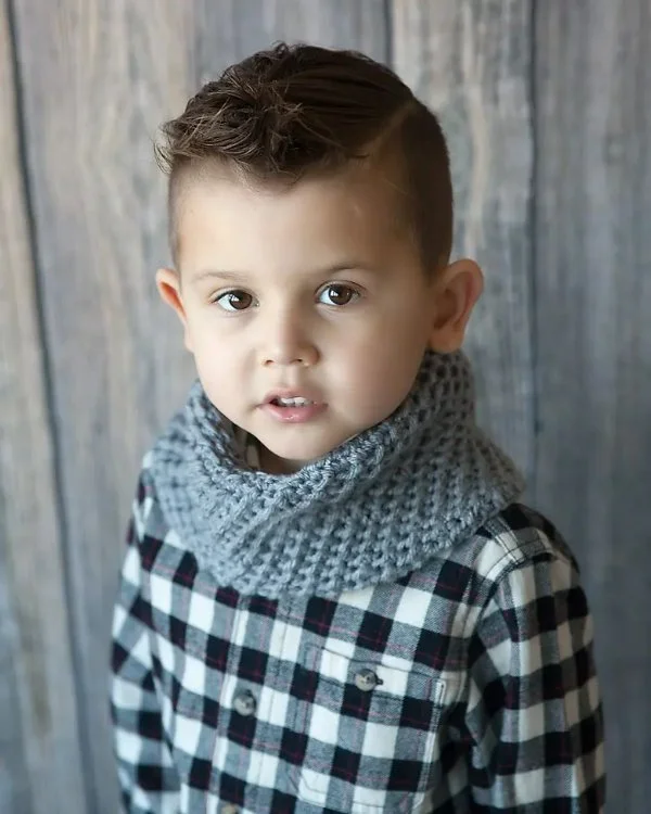 A child in a checked shirt wearing a grey crochet cowl.