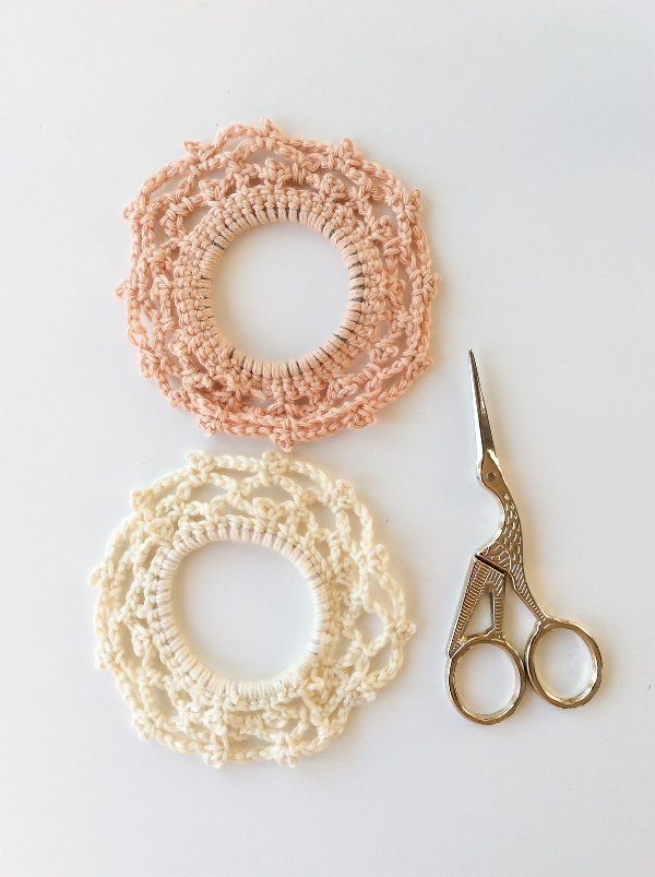 Two lacy crochet scrunchies and a pair of gold embroidery scissors.