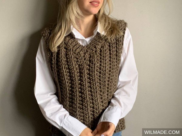 A woman wearing a crochet sweater vest in super bulky weight yarn.
