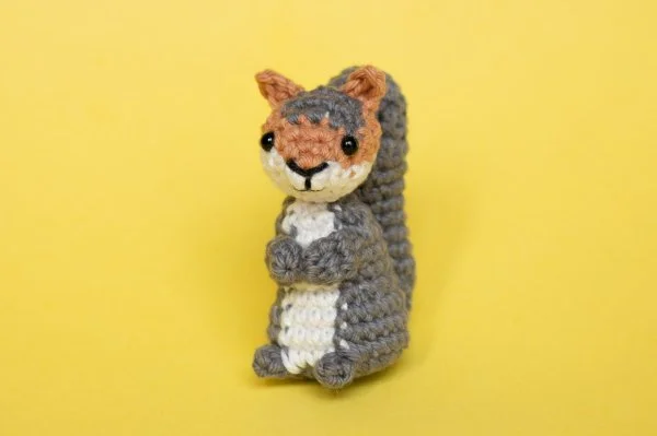 A small crochet squirrel on a yellow background.