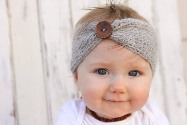 A baby wearing a crochet headband with button detail.