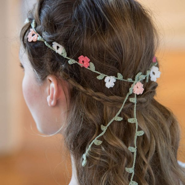 Side view of a crochet floral headband with trailing vine-like leaves.