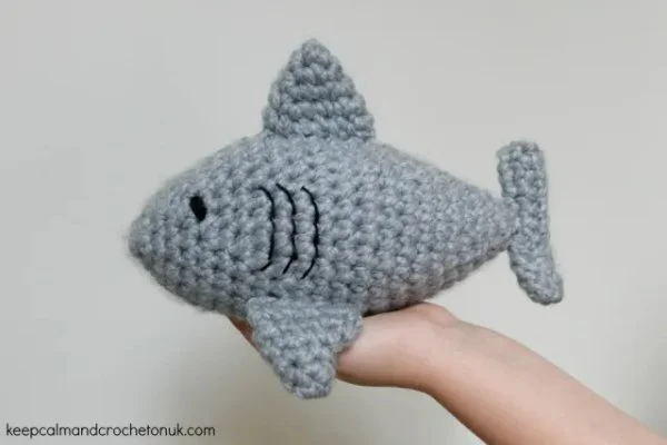 A grey crochet shark worked in chunky weight yarn.