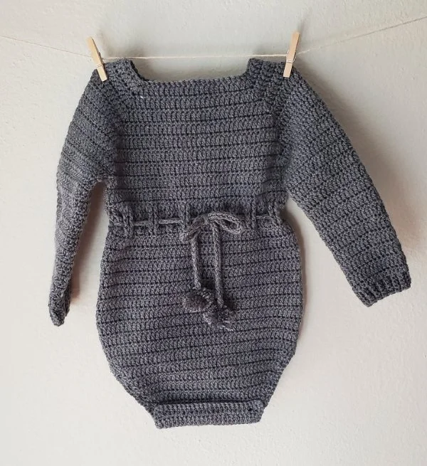 A grey, long-sleeved, crochet baby onesie.