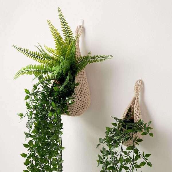 Two crochet plant pods hanging on a wall.
