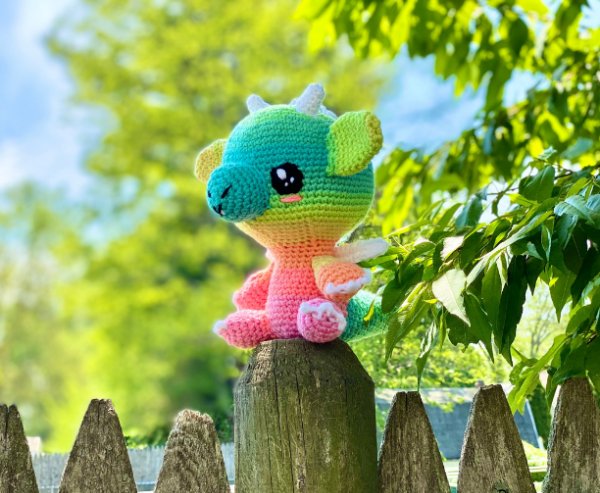 A rainbow crochet dragon made in variegated yarn.
