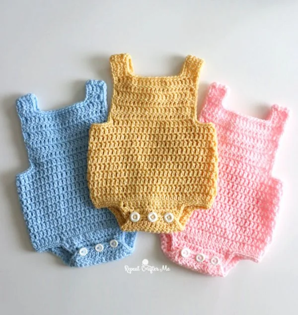 Three simple crochet baby rompers in different colours.