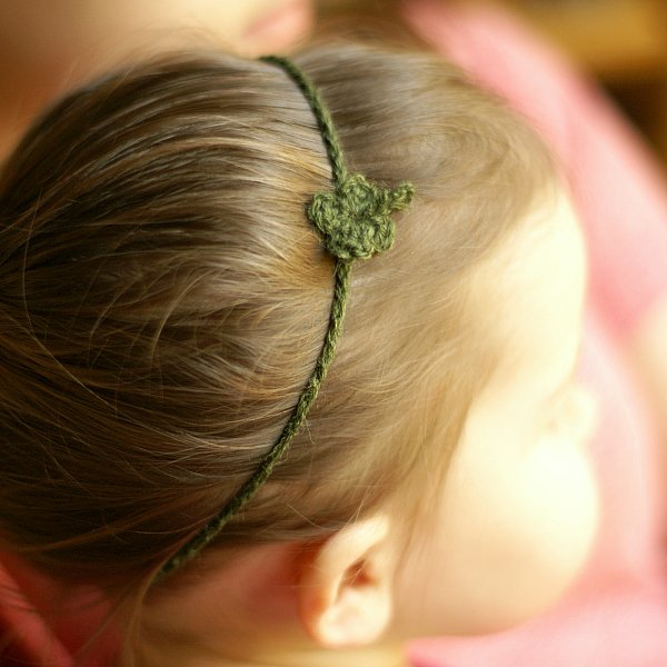 A close-up of a girl wearing a simple crochet headband.