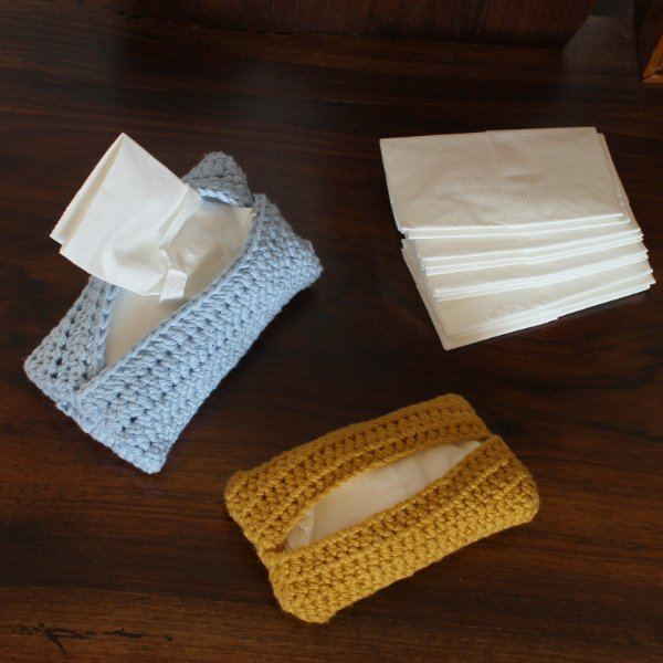 A stack of tissues and two crochet pocket tissue holders.