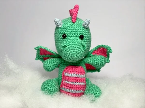 A bright green and pink amigurumi dragon.