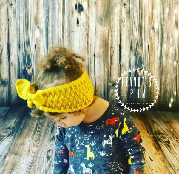 A girl wearing a bright yellow crochet headband.