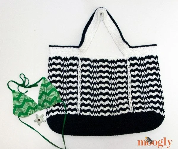 A black and white striped crochet beach bag and a green bikini top.