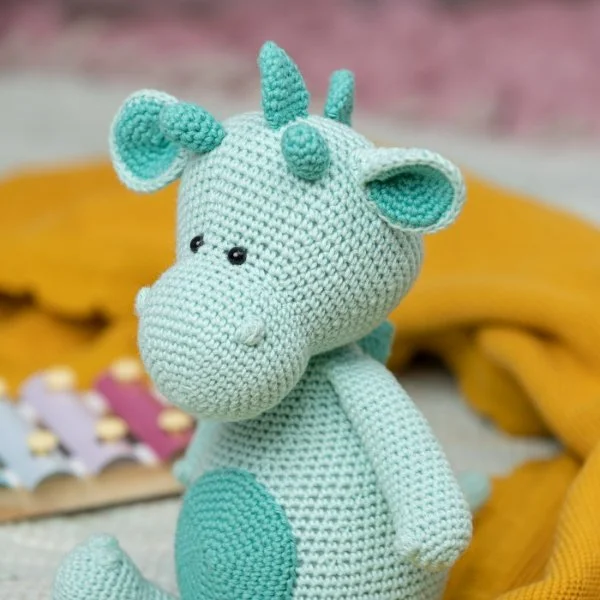 A blue crochet dragon stuffie toy.