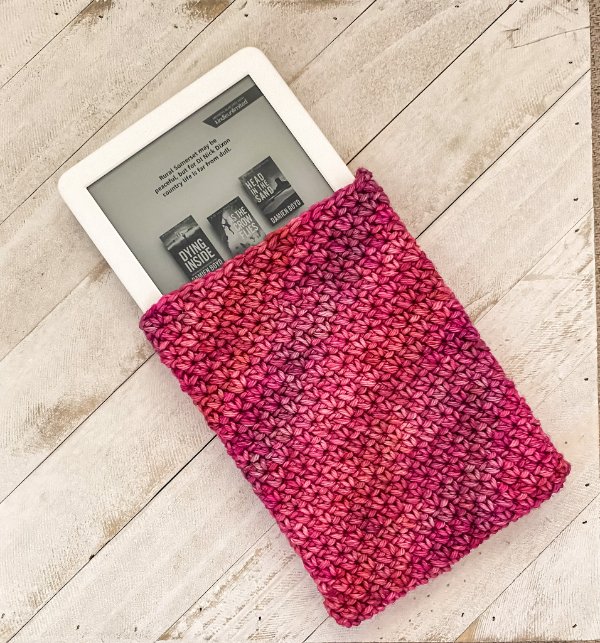 A red crochet case on a Kindle with a timber board background.