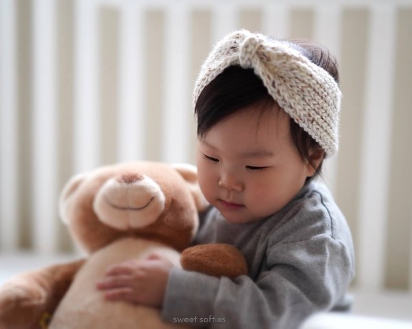Little girl with a teddy and a knit-look crochet headband.