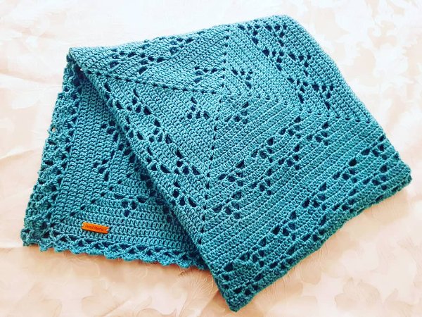 A turquoise filet crochet baby blanket.