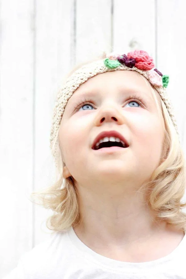 A girl wearing a floral headband with a bright white background.