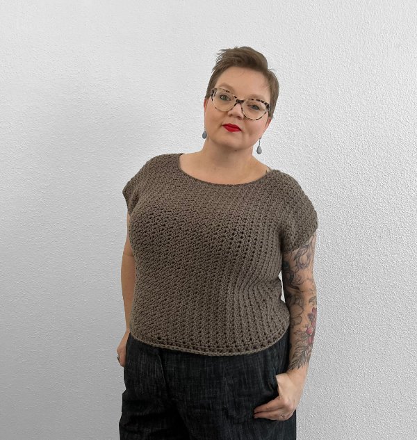 A woman wearing a cropped brown crochet t-shirt.