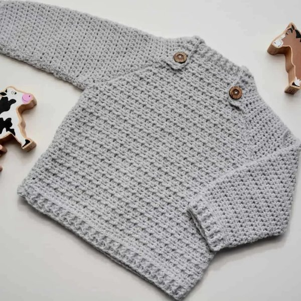 A grey crochet baby sweater with buttons.