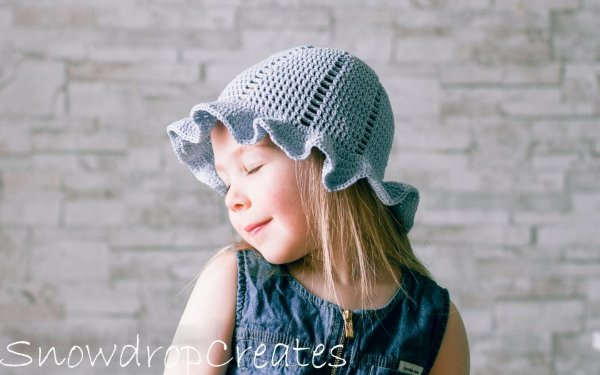 A girl in a blue frilly crochet sun hat.