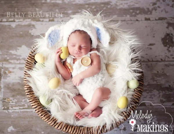 A newborn baby in a matching crochet baby romper and crochet lamb hat in a fur-lined basket.