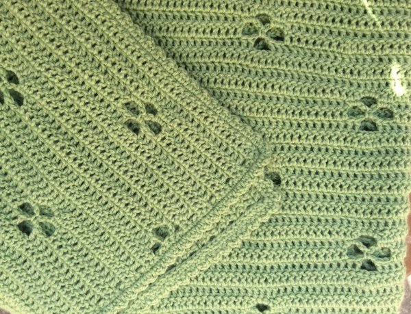 A closeup of a simple green filet crochet baby blanket.