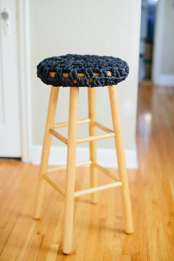 A dark blue crochet stool cover on a blonde timber bar stool.