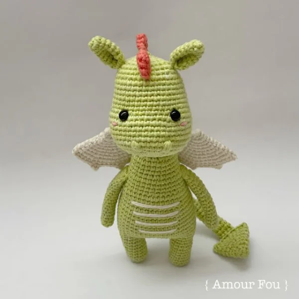 A green crochet dragon with pink spikes.