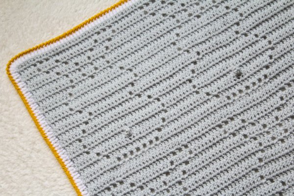 Grey crochet bunny blanket with yellow edging.