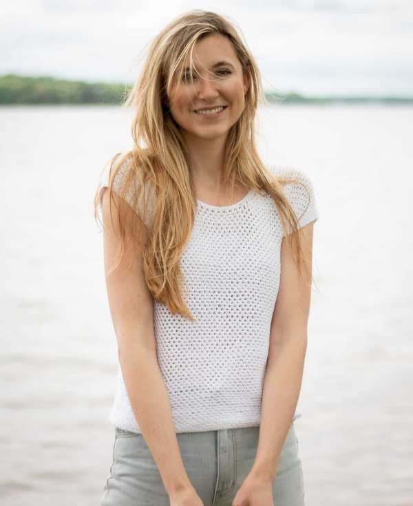 A woman in a simple white crochet tee with a round neck.