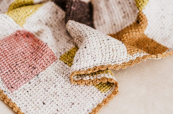 Closeup of a patchwork Tunisian crochet baby blanket.