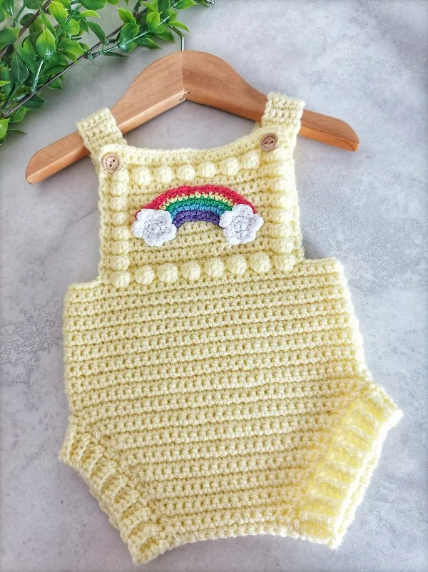 A lemon yellow crochet baby romper with rainbow crochet applique.