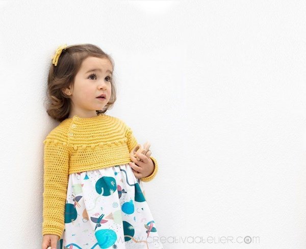 Crochet toddler dress with a fabric skirt.