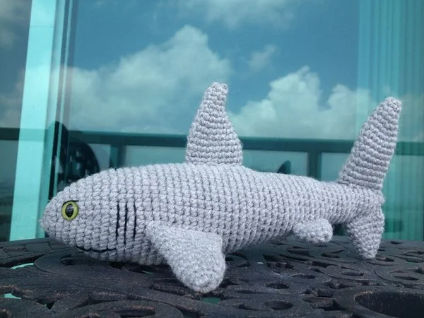 A grey crochet shark with green eyes.