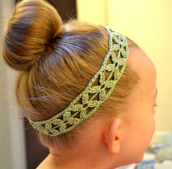 Side view of a young girl wearing a green crochet headband.