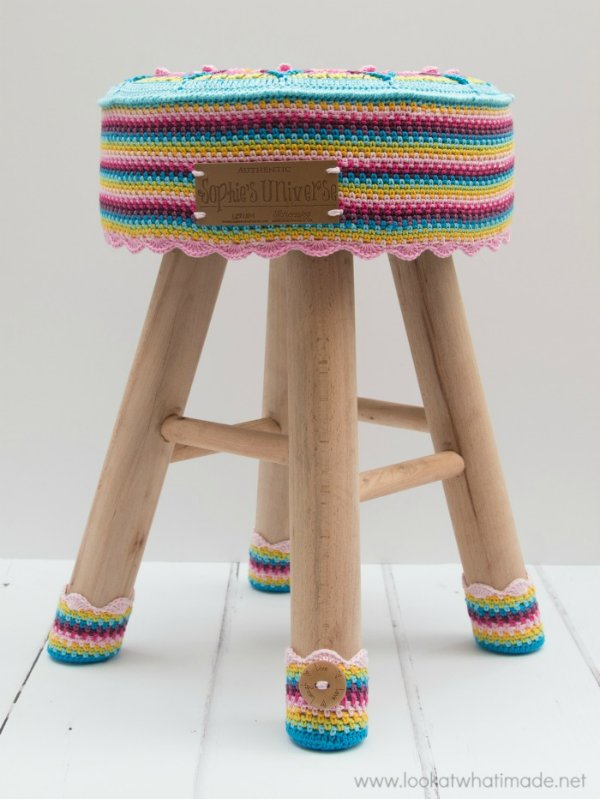 A stool with a stripey crochet cover and crochet chair socks.