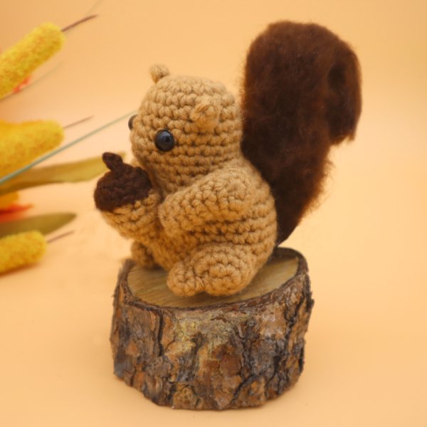 A little crochet squirrel amigurumi holding an acorn.