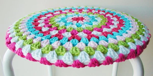 A closeup of a multicoloured granny stitch crochet stool cover.