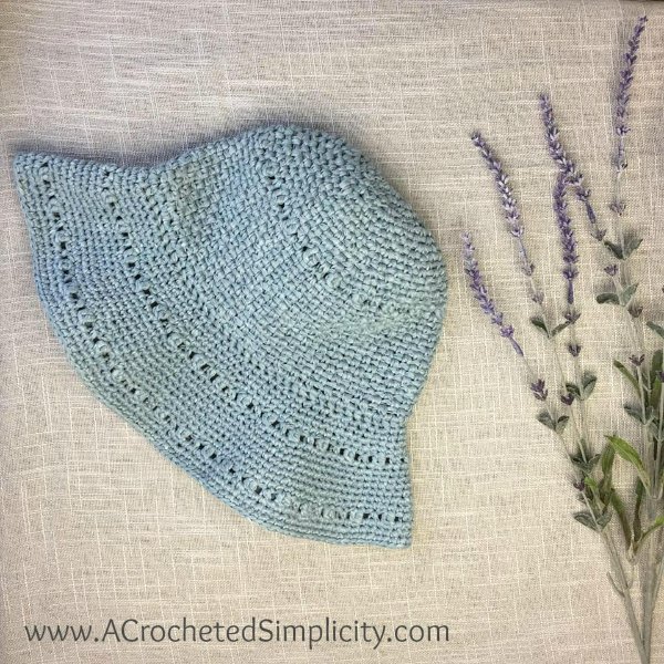 A blue crochet sun hat with a lavender sprig.