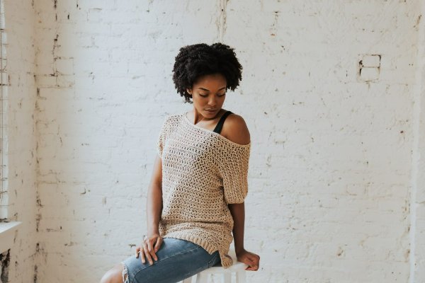 A woman wearing a crochet tee off-shoulder.