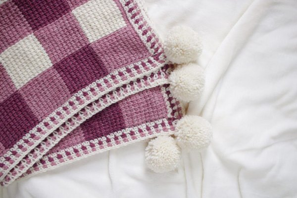 A pink gingham Tunisian crochet baby blanket.