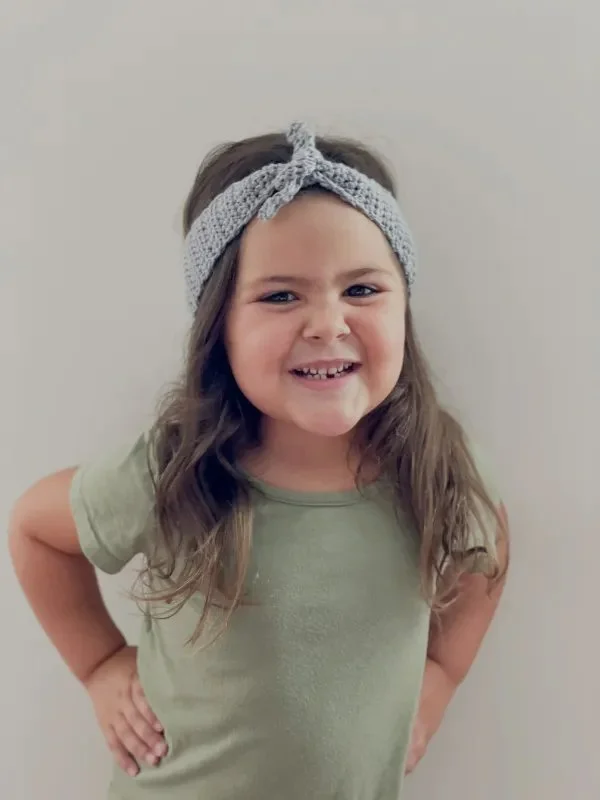 A girl wearing a knot-tie crochet headband.