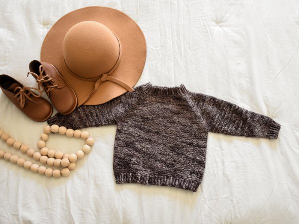 A brown crochet baby sweater with little shoes and a hat.