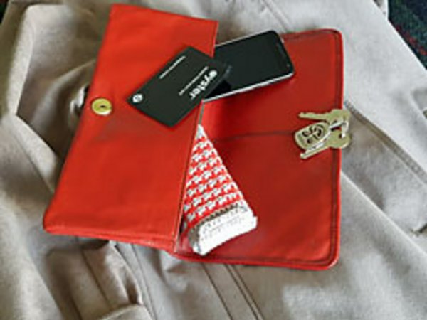 A crochet pocket tissue cover with a jacket, a red purse and a set of keys.
