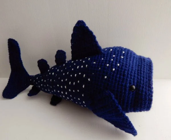 A crochet whale shark worked in dark blue and white yarn.