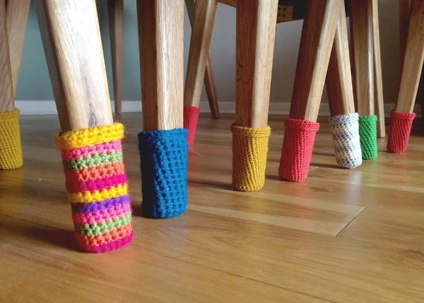 Crochet chair socks in bright colours on chairs.